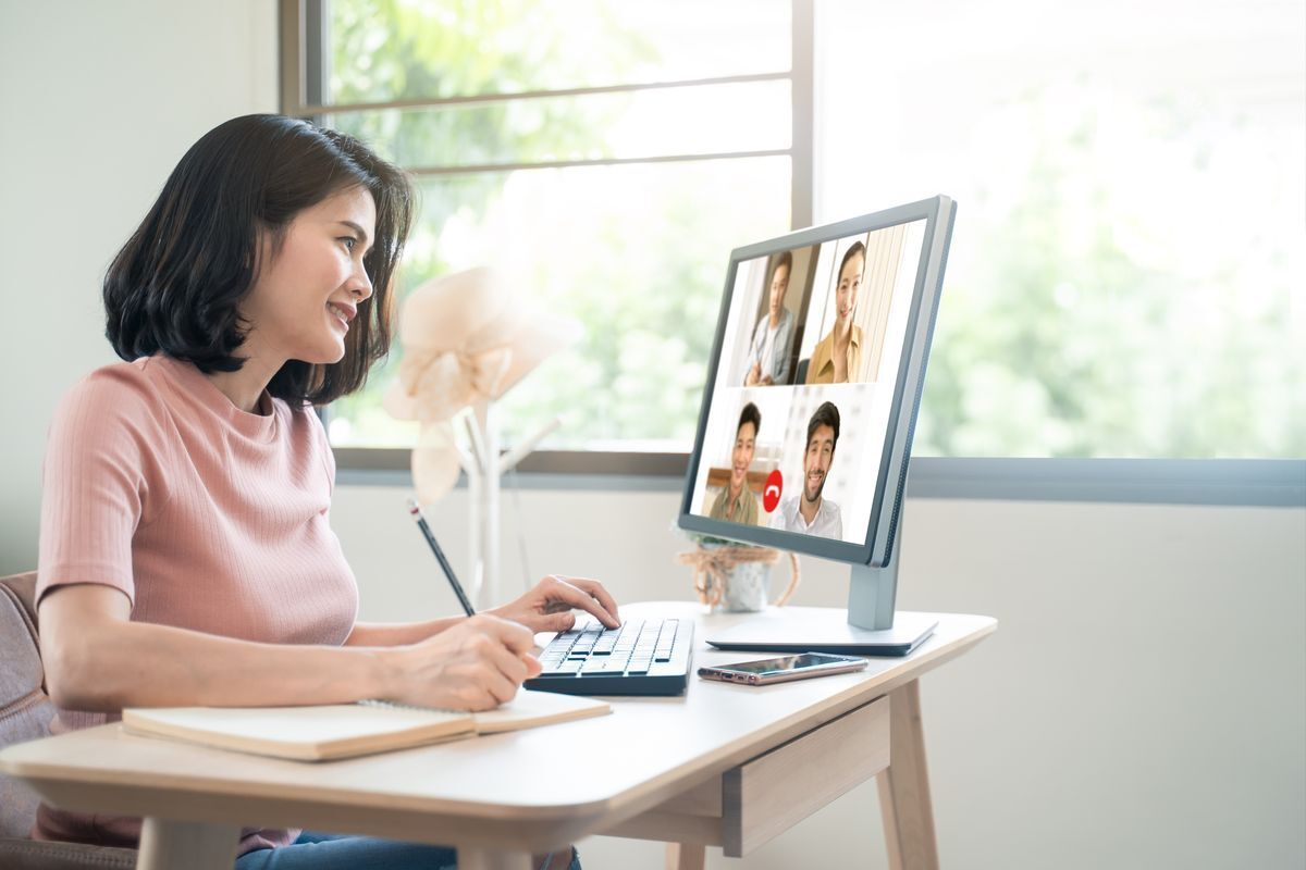 Asian woman with short hair talking to colleagues on a video call. 