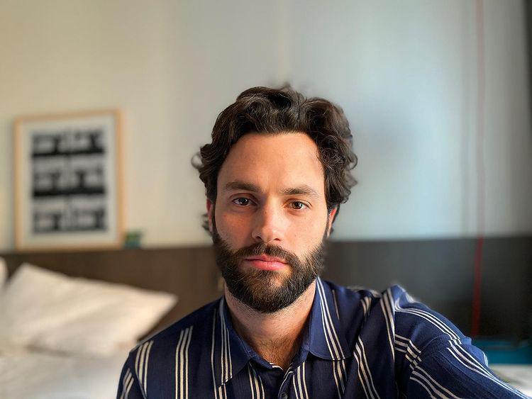 Penn Badgley with a thick beard and curly hair