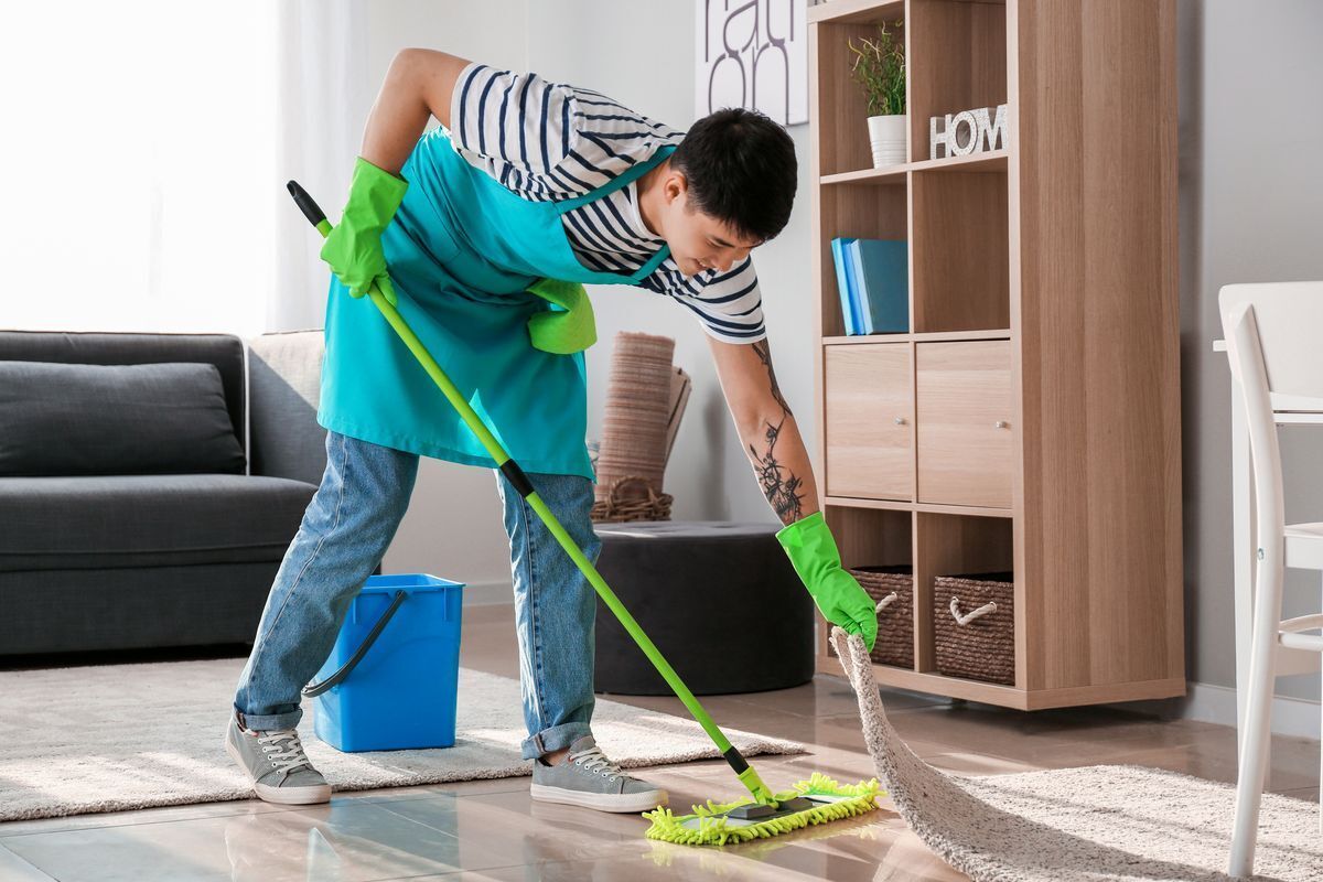 Filipino man smiling while cleaning the floor