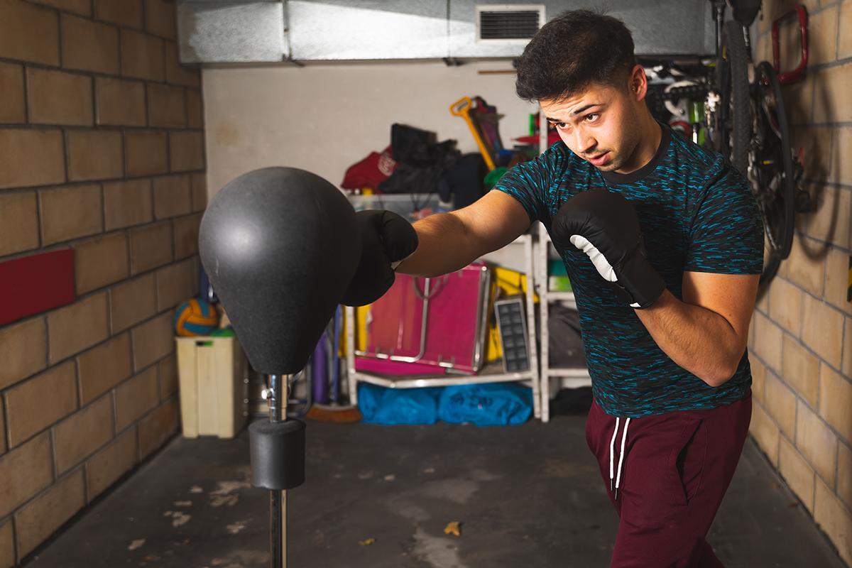 Young man punching a punching bag in his garage.