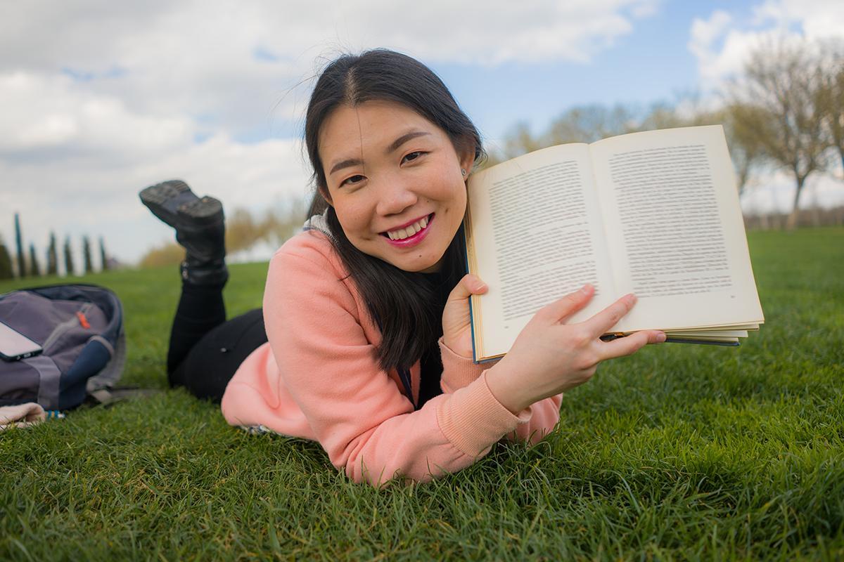 Asian girl with book on grass