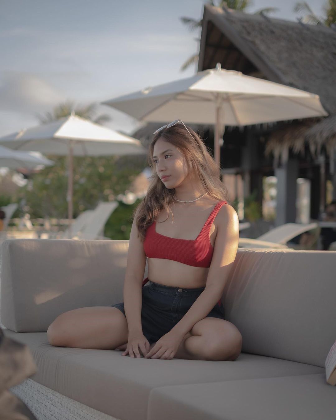 Pretty Asian woman in bathing suit on couch.