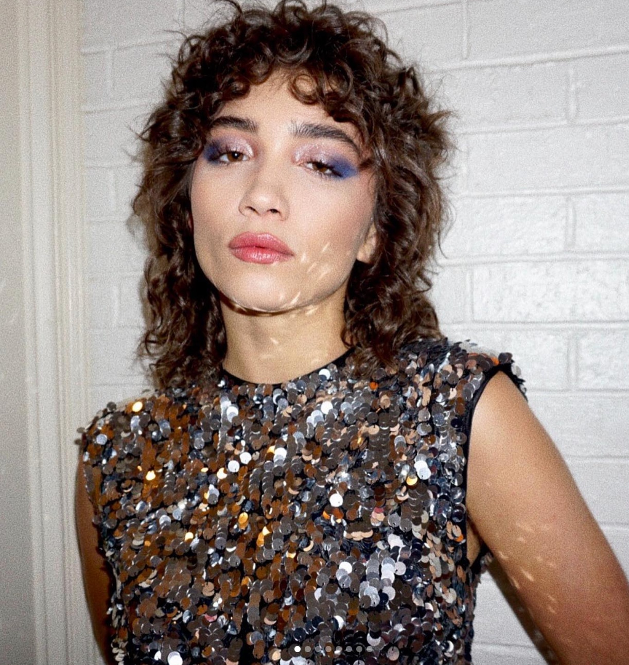 Woman with curly hair and sequined top
