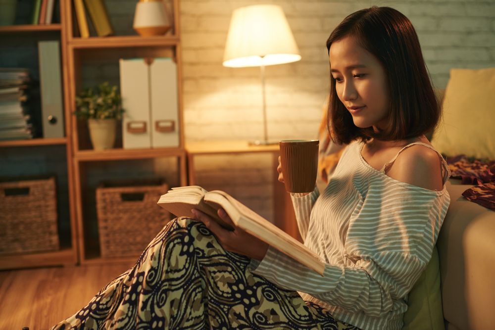 Asian woman reading a book indoors.