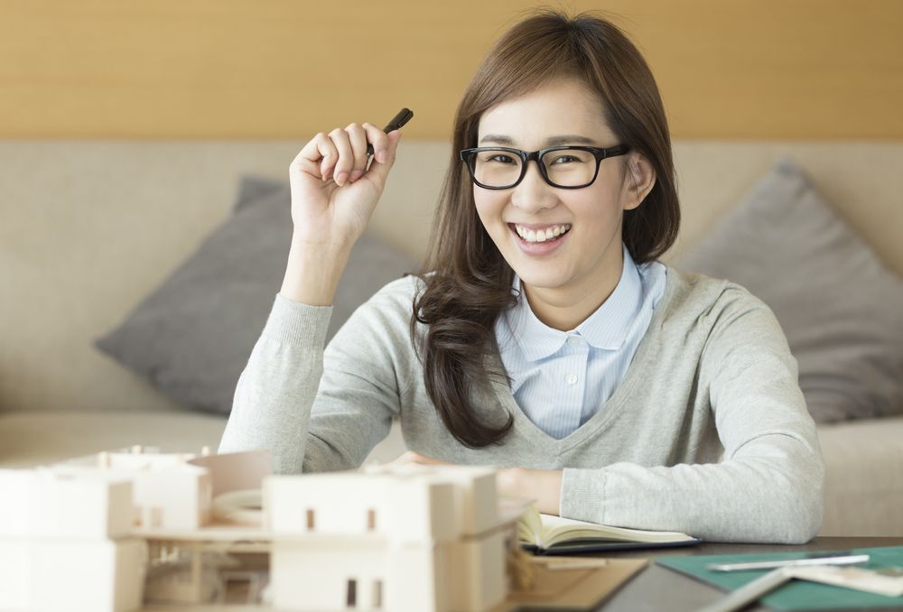 An Asian woman with glasses smiling while working