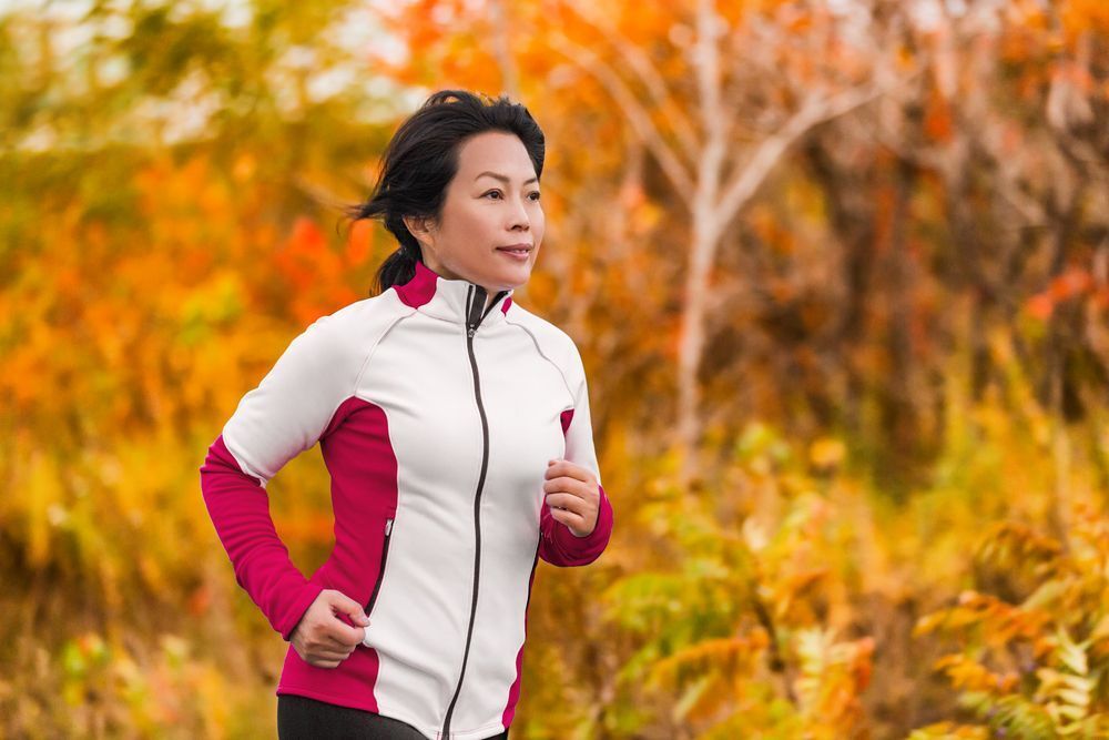 Active middle aged Asian woman jogging 