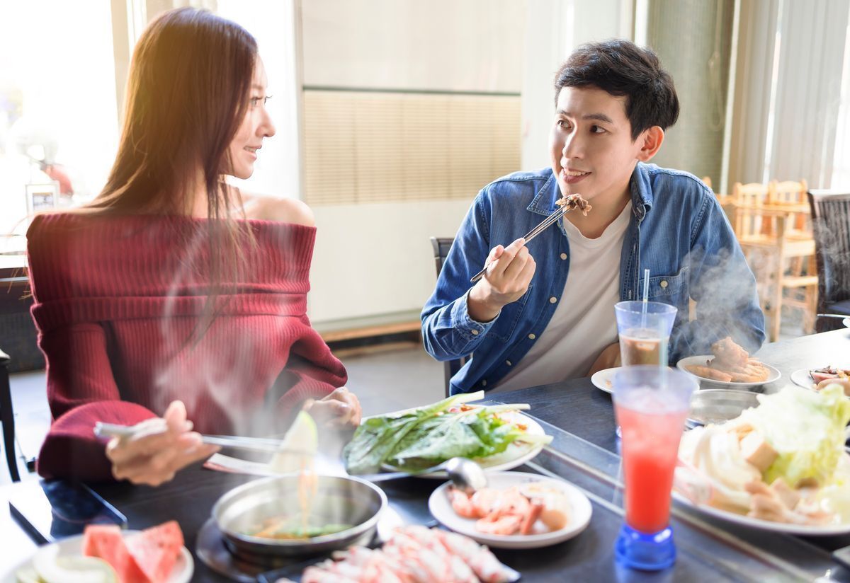 Two young friends having a hot pot dinner in a restaurant