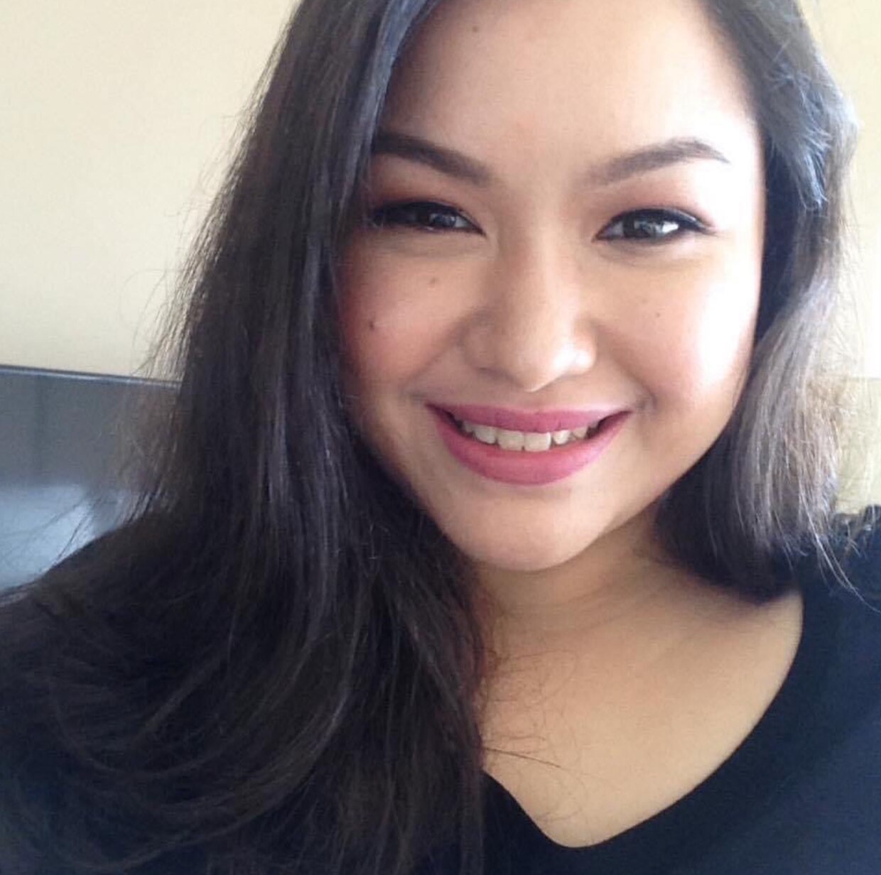 Portrait of an Asian woman with wavy hair smiling. 