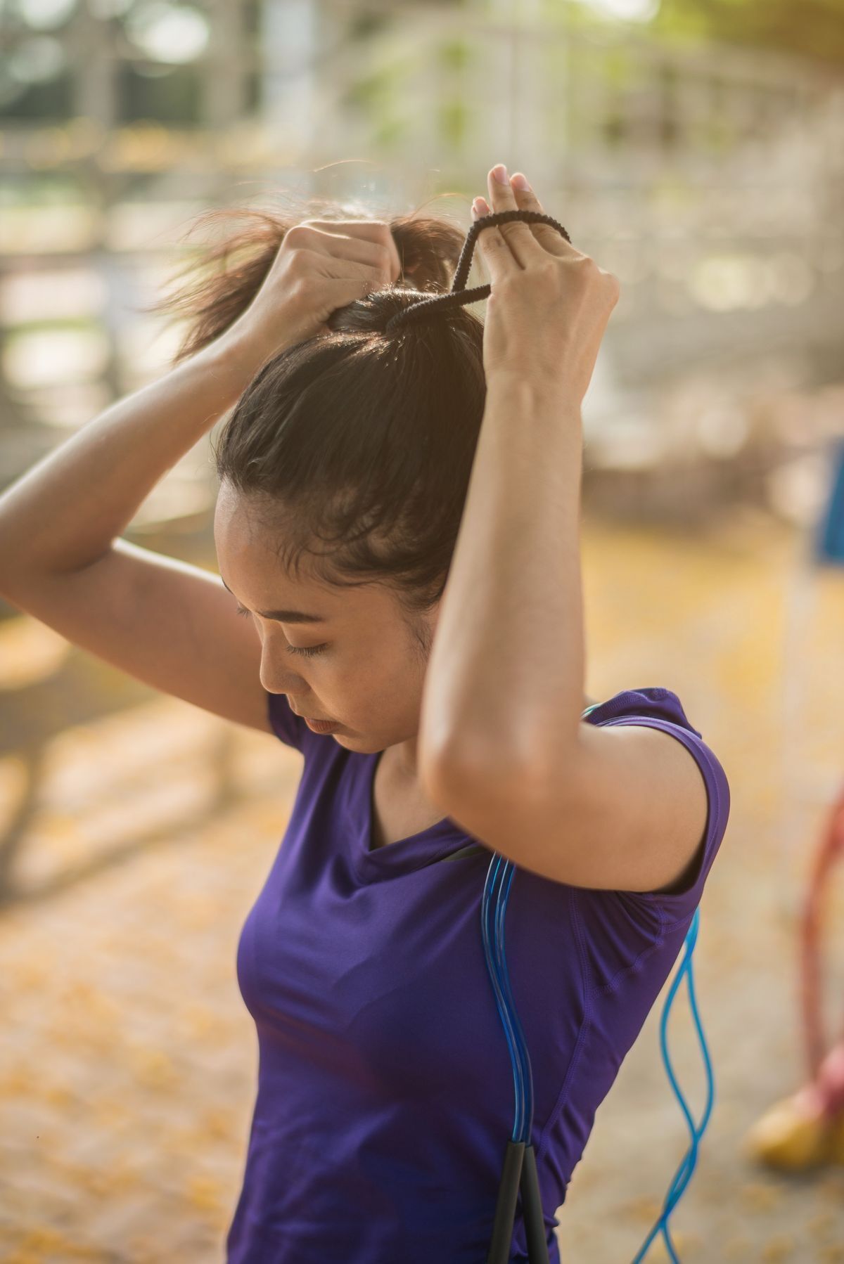 Asian woman tying hair into a ponytail