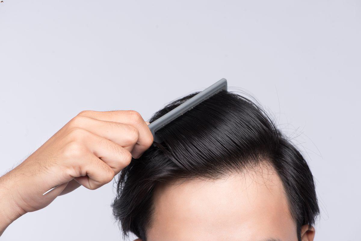 Asian man combing hair 