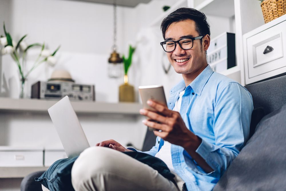  An office worker smiling while looking at his smartphone