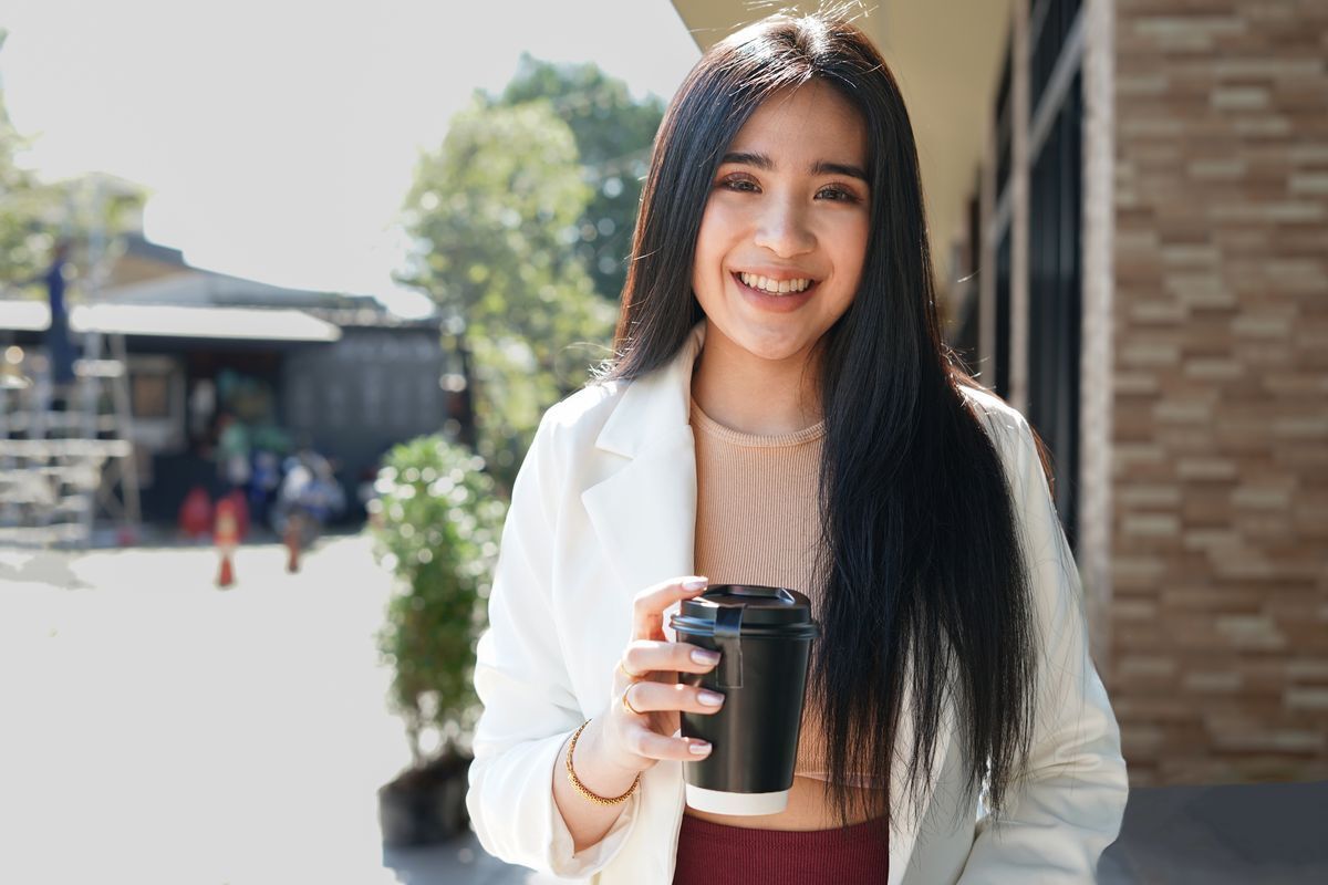Asian woman with long hair holding a coffee cup