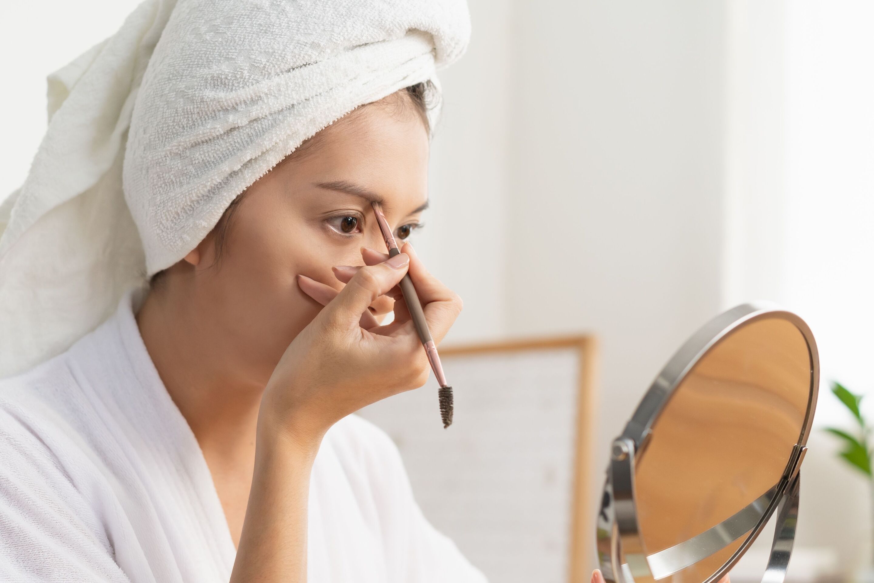 Woman drawing her eyebrows with a small brush.
