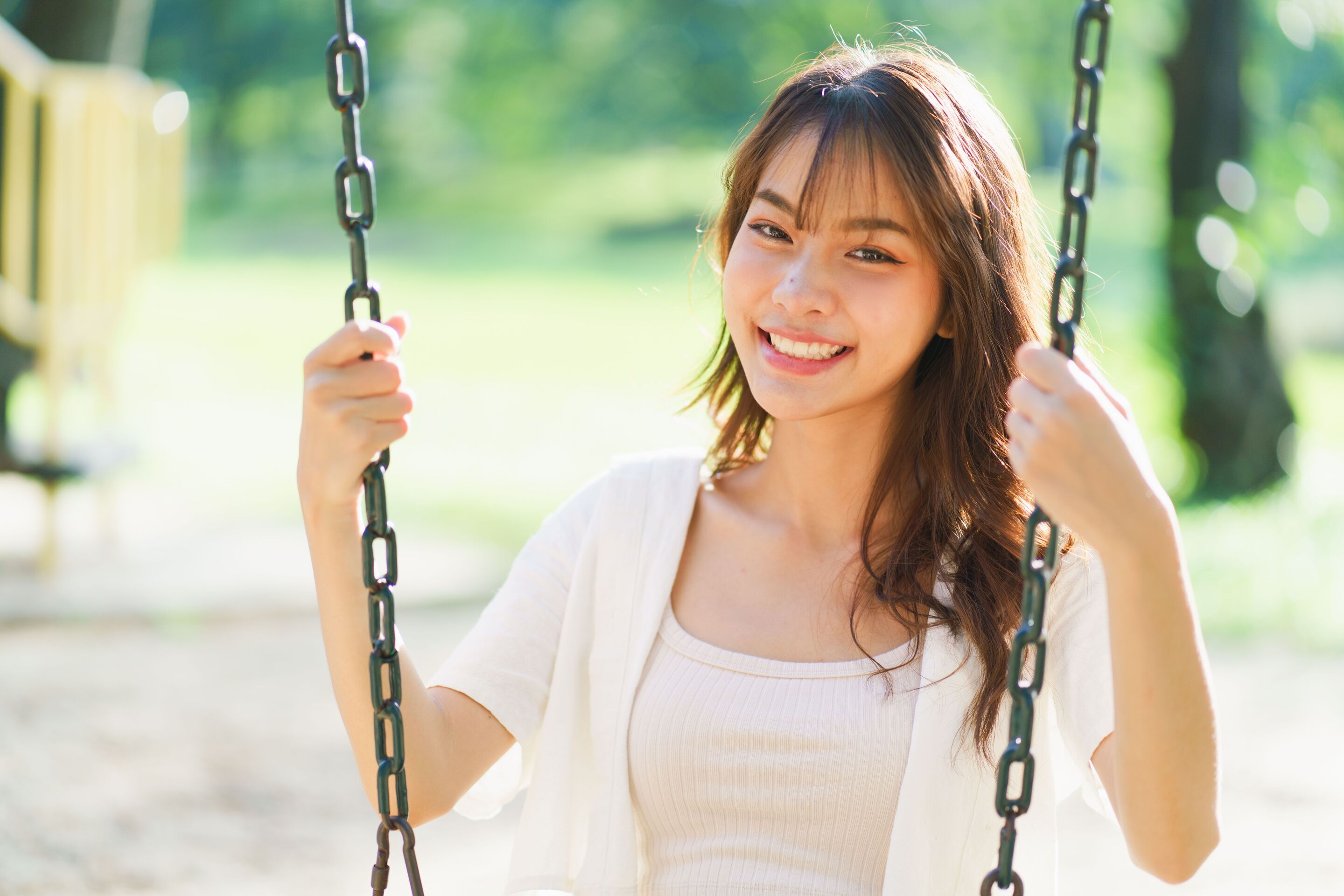 Smiling woman on a swing in an outdoor park.