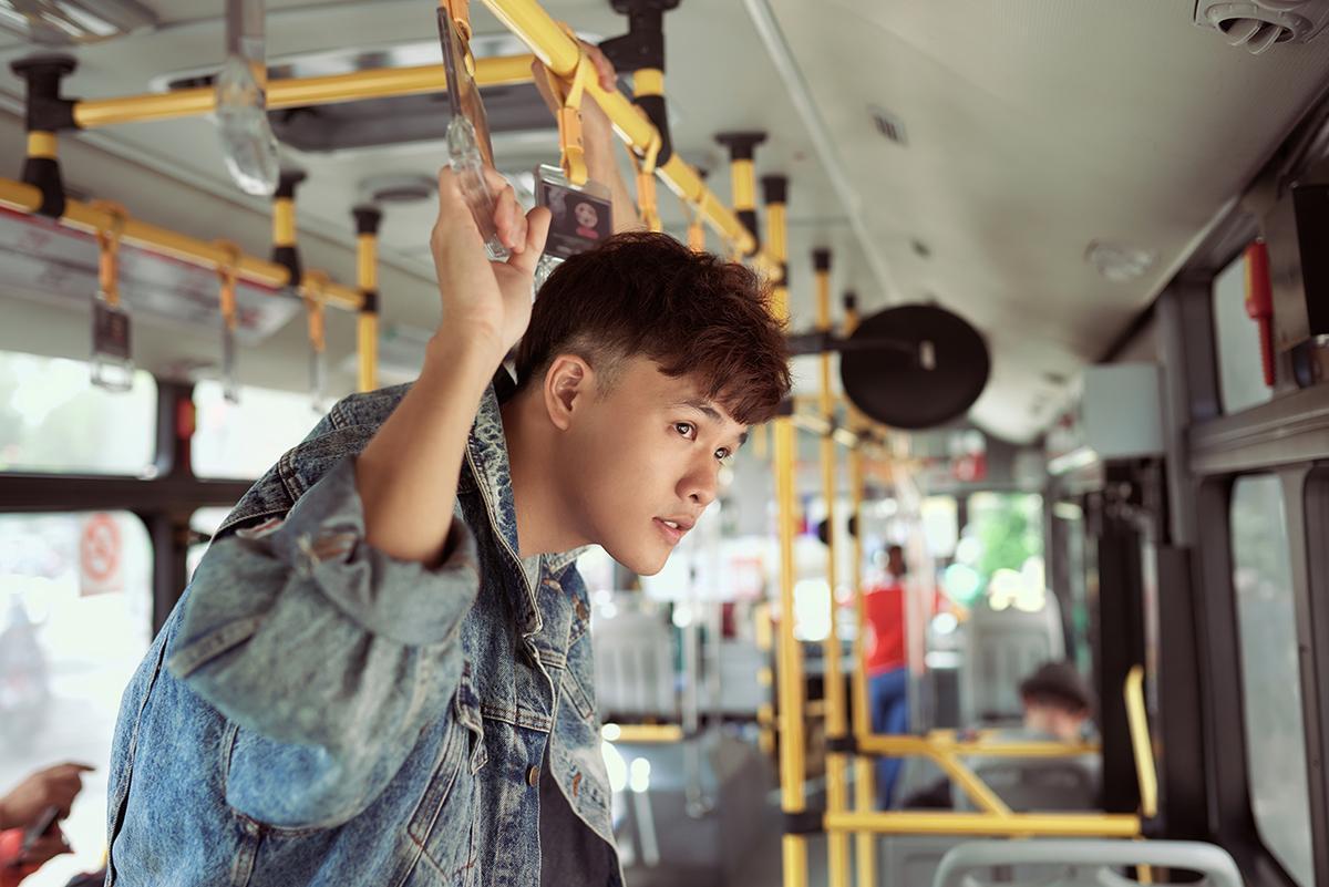 Asian man holding on while riding a bus 