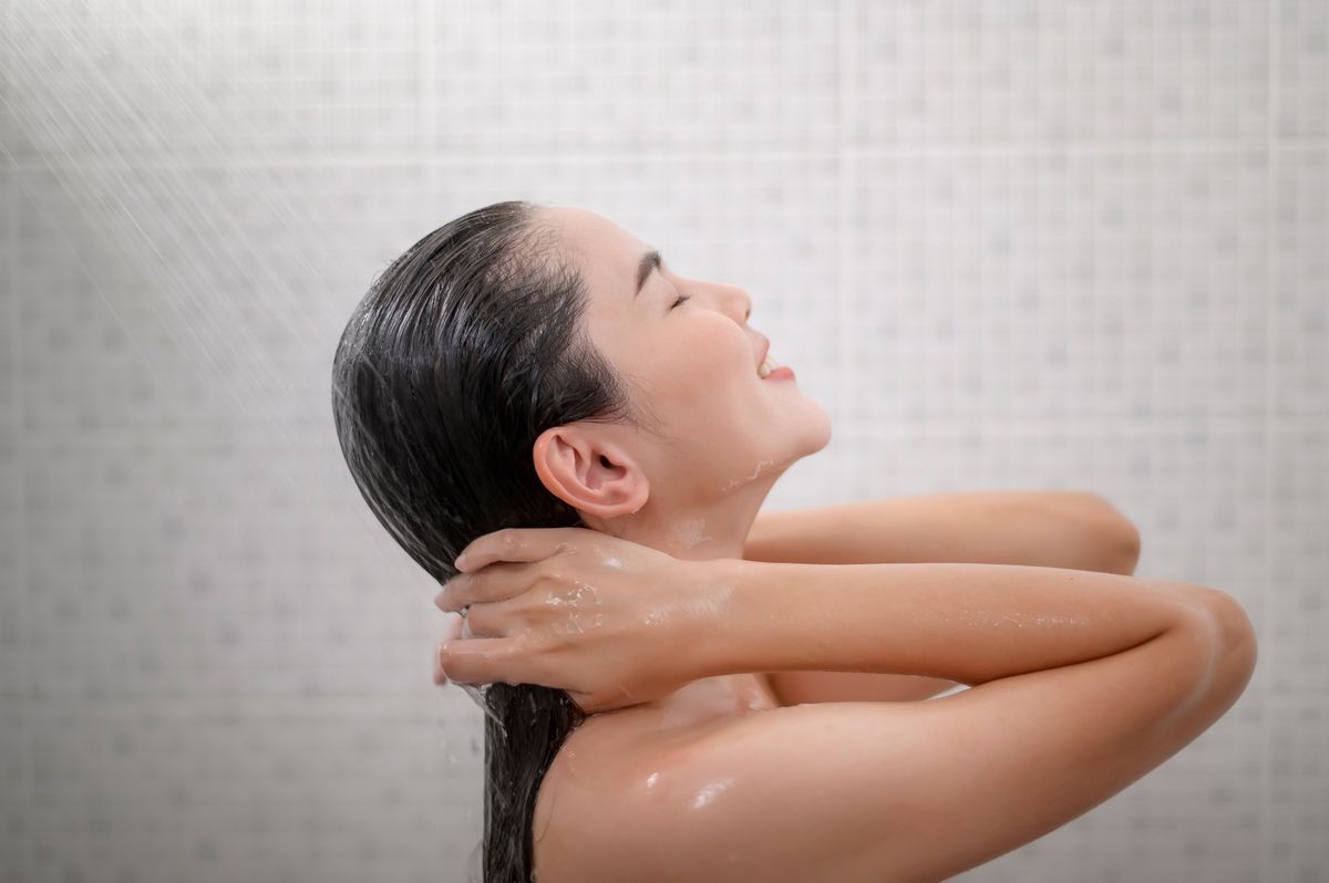 Young Asian woman in the shower, shampooing her hair
