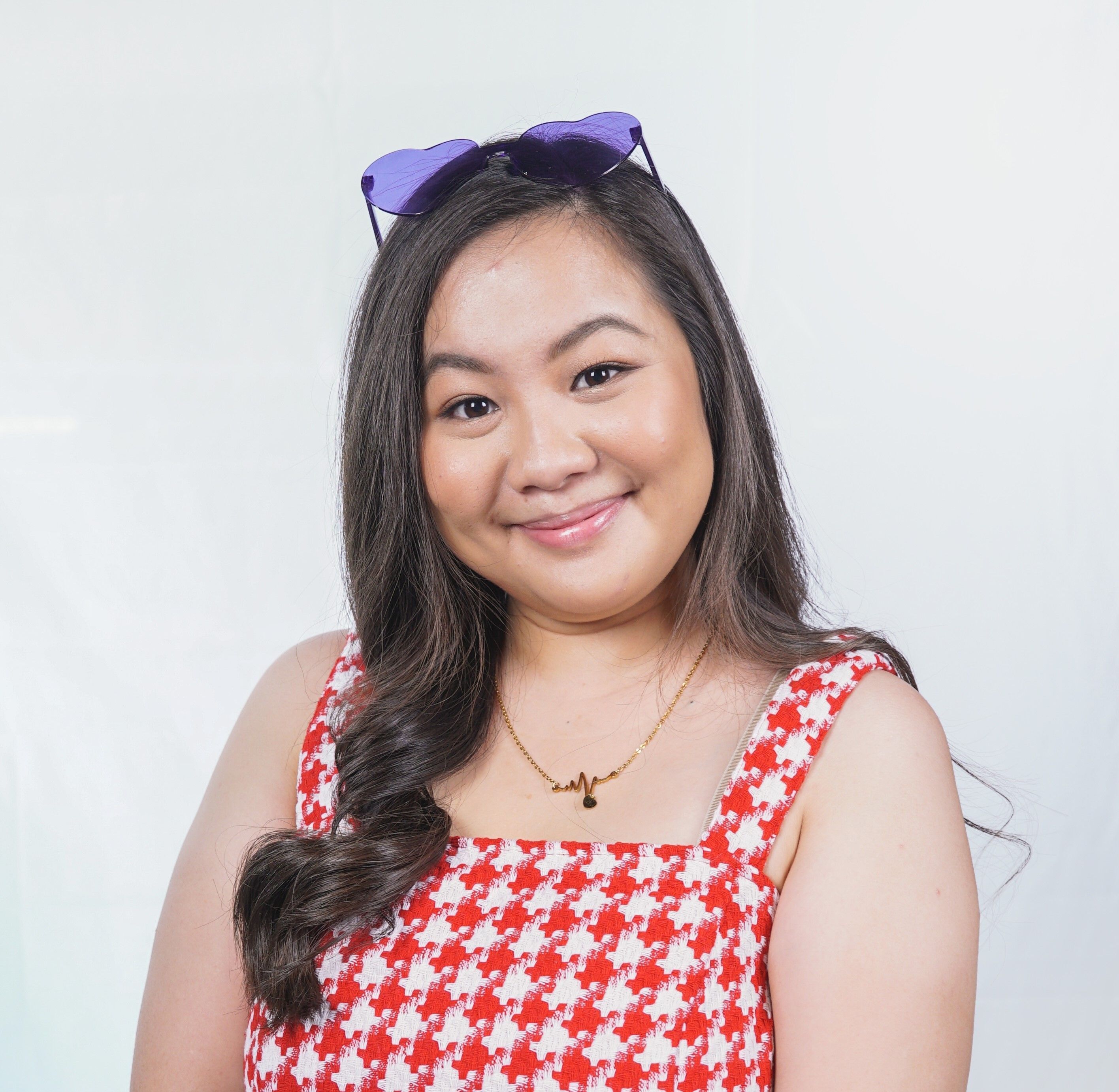 A portrait of a woman with long brown hair wearing red gingham dress.