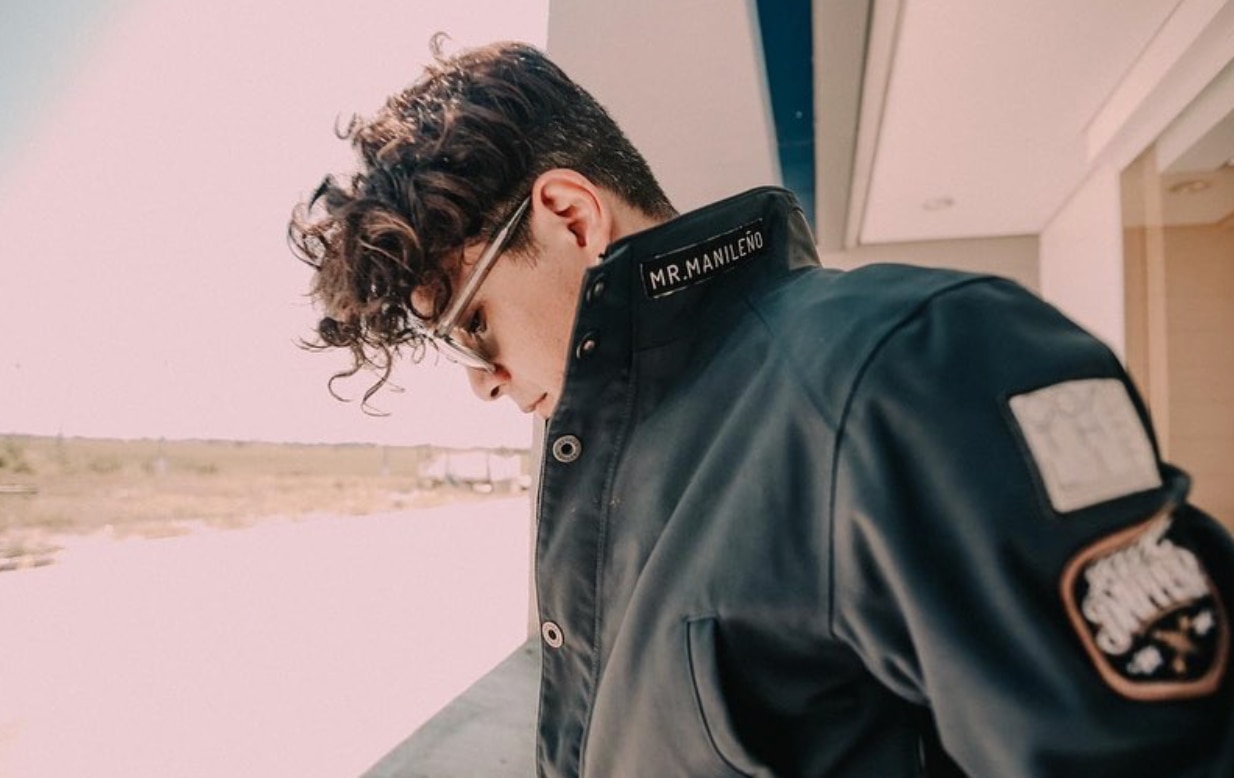 Asian man with curly hair wearing a moto jacket. 