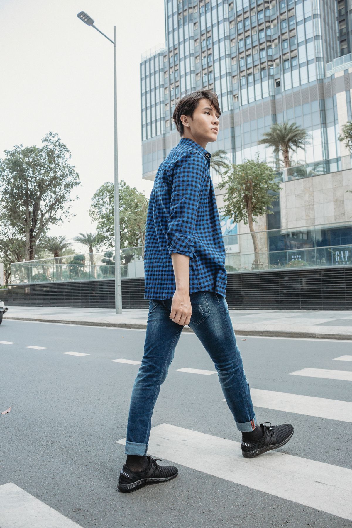 Young Asian man walking on pedestrian lane.