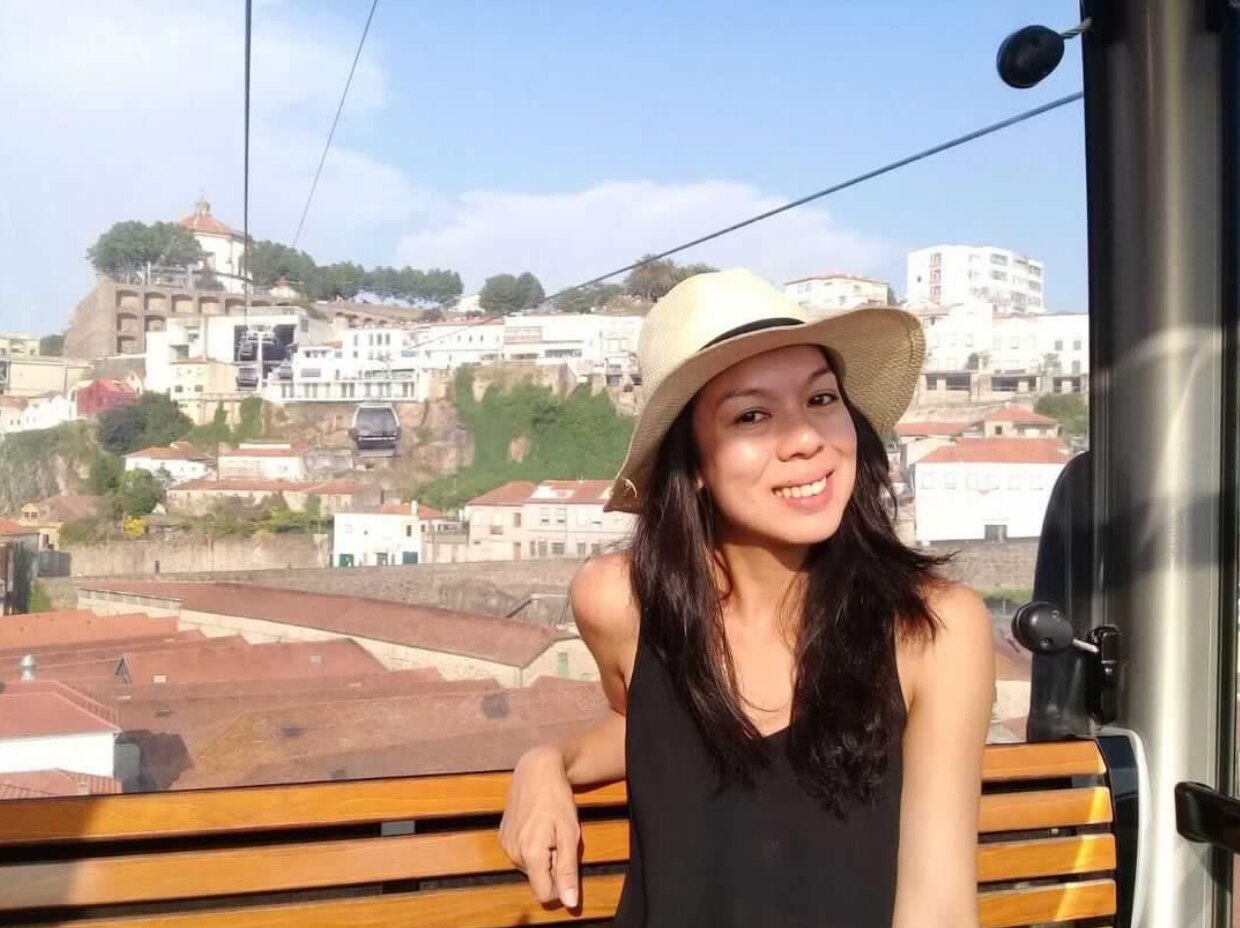 Smiling Asian woman wearing a straw hat in a cable car.