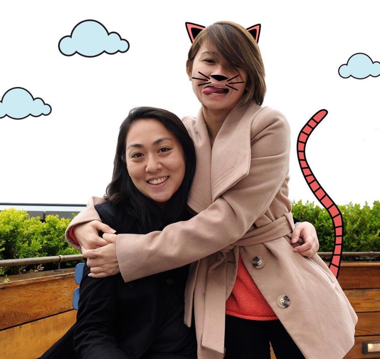 Graphic art of 2 Asian girls smiling with graphic art drawn on one of them with a cat’s ears, whiskers, and tail