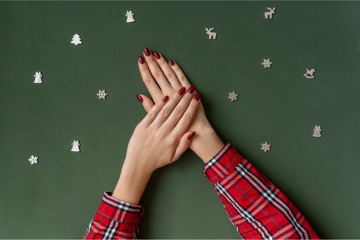 nail màu mận đỏ bàn tay mặc áo kẻ caro màu đỏ móng màu đỏ mận trên nền xanh lá đậm 