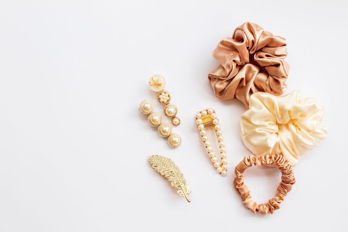 scrunchies là gì scrunchies màu nâu màu kem và size nhỏ màu nâu kem kế bên ba chiếc kẹp tóc màu vàng ngọc trai trên nền trắng