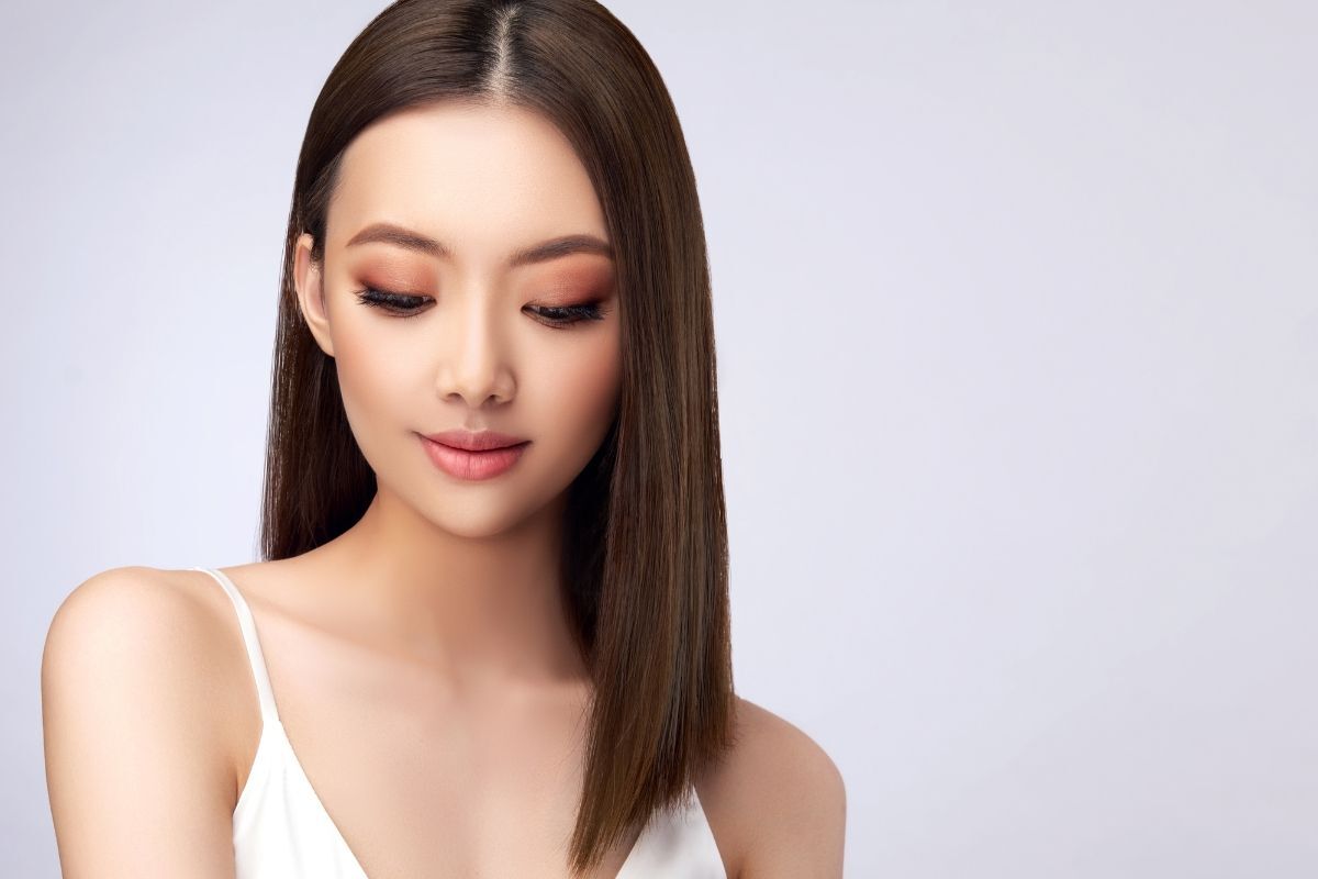 Tóc nâu đen cô gái có mái tóc dài ngang vai rẽ ngôi giữa đang nhìn xuống dưới