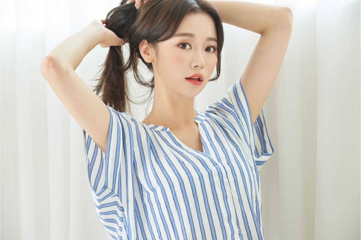 tóc mái bay layer cô gái mặc áo kẻ sọc xanh trắng bới tóc nhìn thẳng vào ống kính 