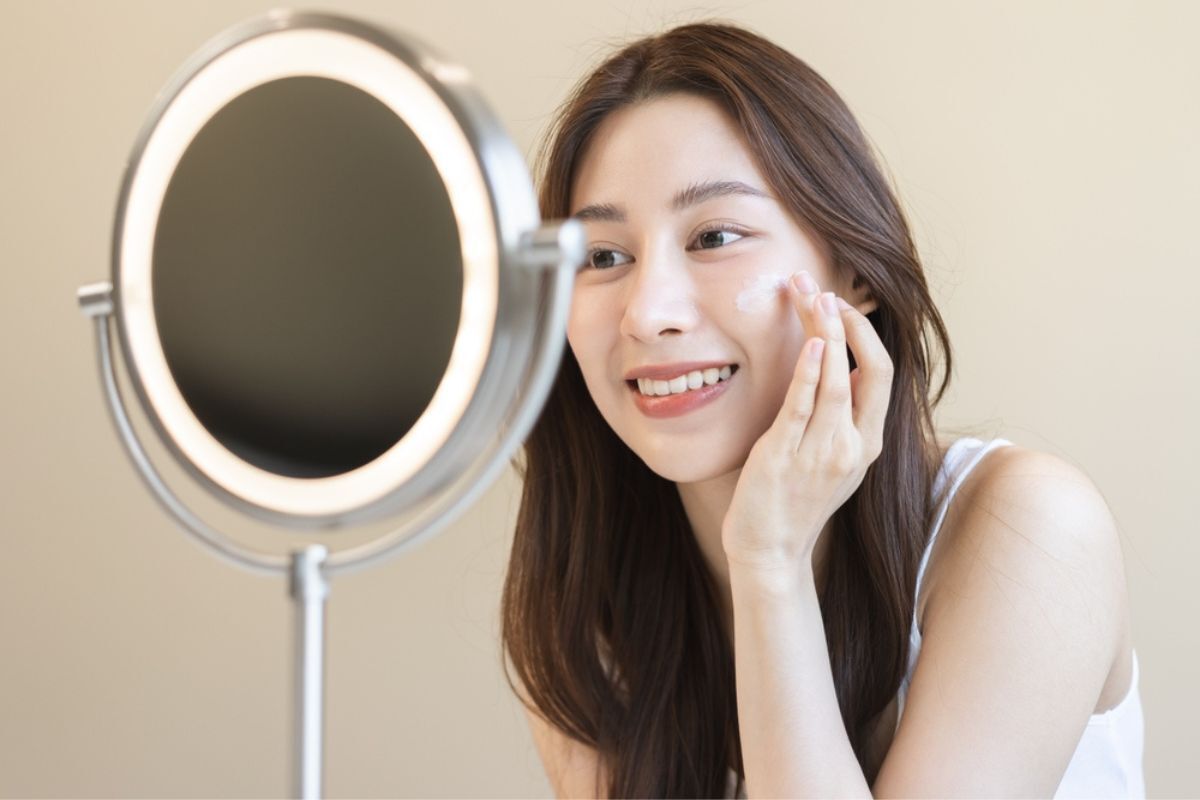 Bakuchiol kiên trì dùng Bakuchiol hàng ngày cô gái đang cười tươi thoa kem dưỡng lên má