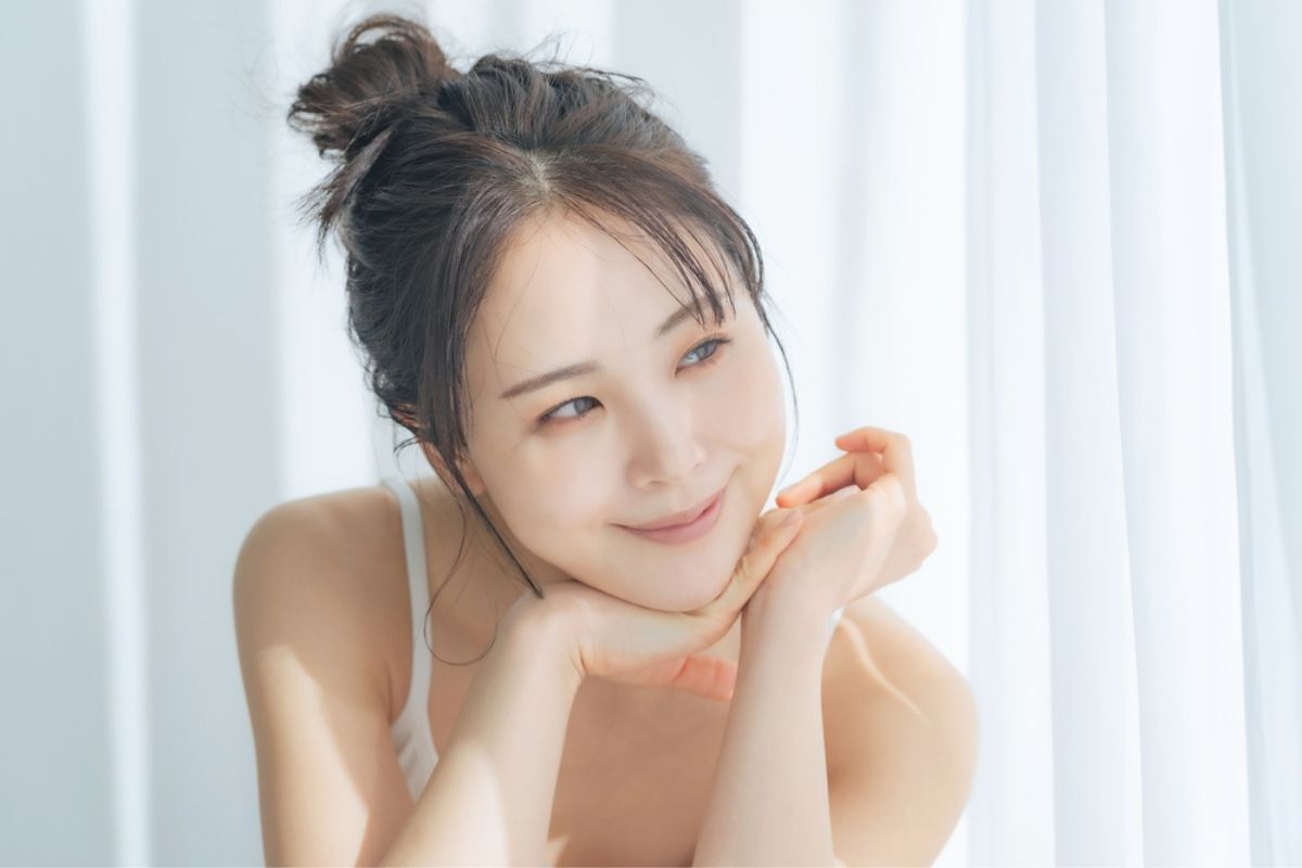 Bakuchiol bảo vệ da khỏi ánh nắng cô gái mỉm cười bên cạnh cửa sổ có rèm trắng