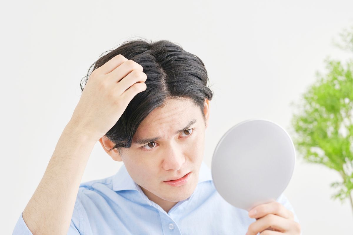 dầu gội trị gàu chàng trai đang soi gương