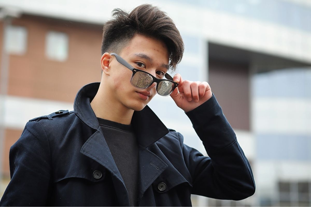 Chàng trai đeo kính mát màu đen và mặc áo khoác màu xanh đậm 