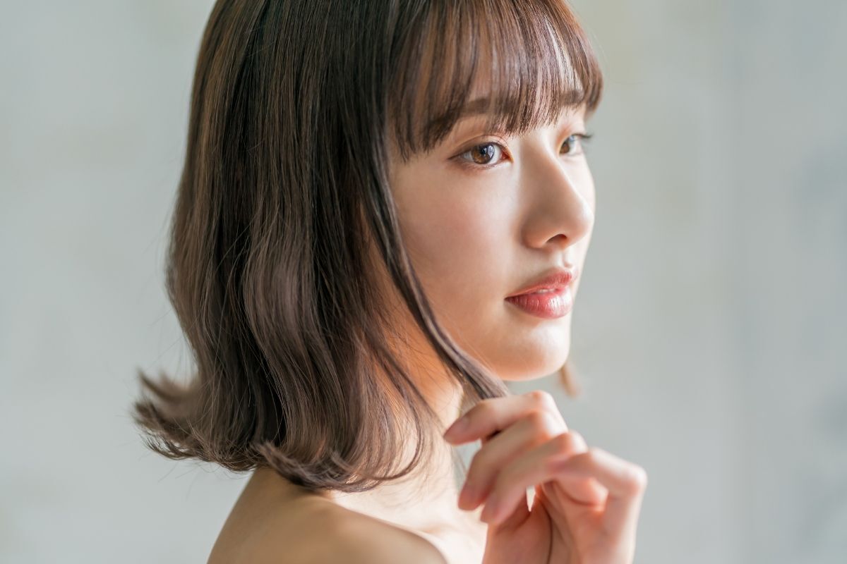 Kiểu tóc xoăn đuôi cho học sinh chân dung cô gái để tóc ngắn uốn cụp đuôi chụp trên nền tường màu xám