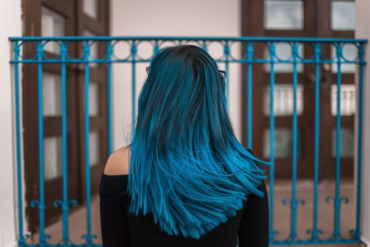 Nhuộm tóc xanh dương cô gái đứng quay lưng trước mặt là hàng rào