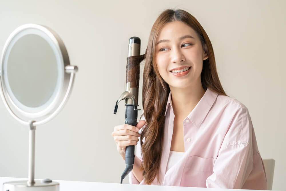 tóc sâu cô gái đang làm xoăn tóc bằng máy uốn