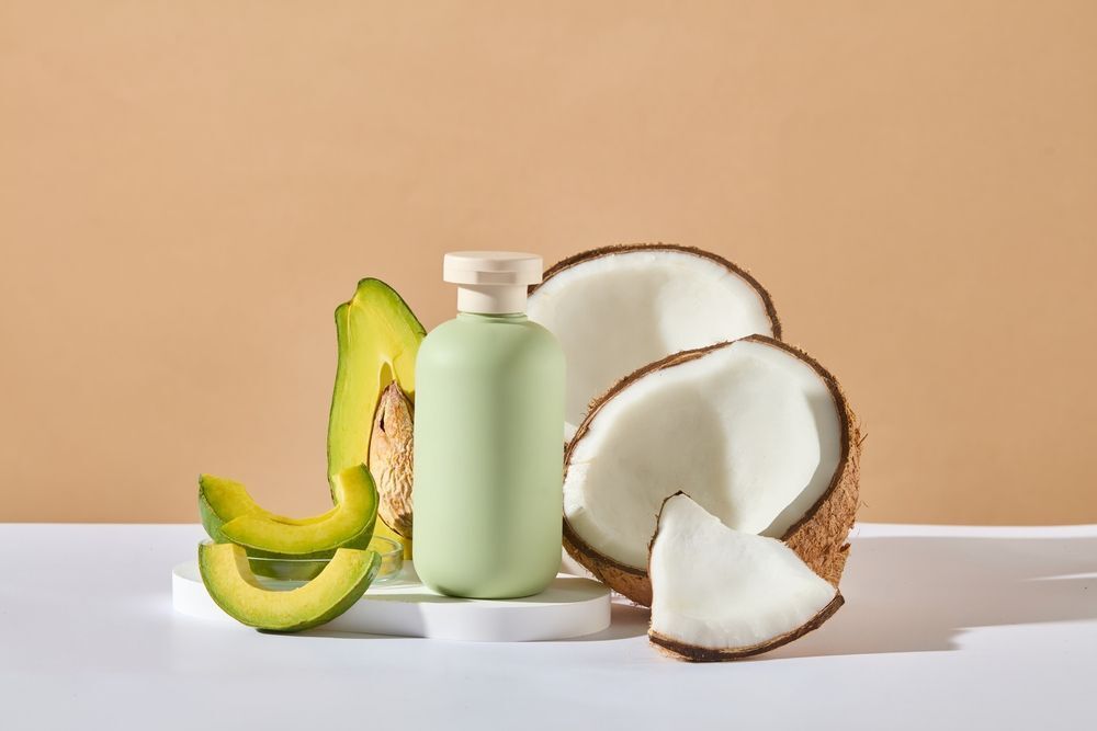  tại sao gội đầu xong vẫn có gàu chai dầu gội màu xanh lá chuối nhạt kế bên các lát bơ và quả dừa chẻ đôi