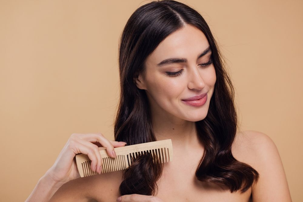 tại sao gội đầu xong vẫn có gàu cô gái cầm lược chải phần đuôi tóc nhắm mắt cười mỉm