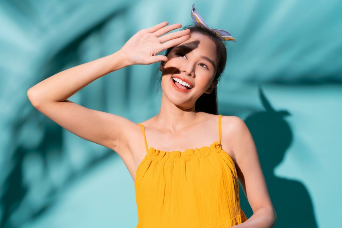  cô gái mặc áo vàng đang giơ tay che nắng