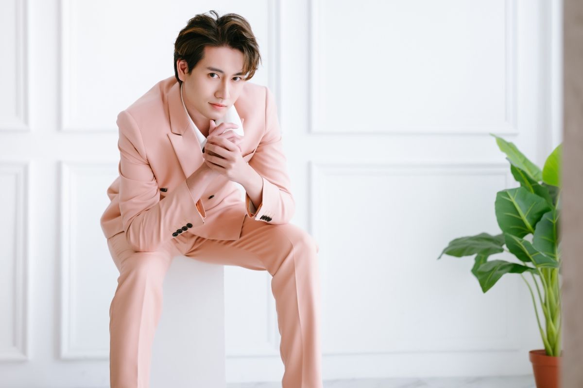 phối đồ tết cho nam chàng trai ngồi trên bục trắng mặc vest hồng