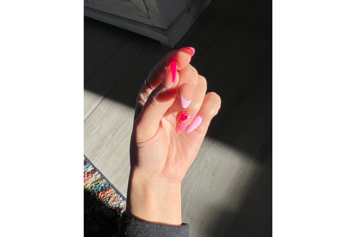 Nail màu hồng thạch bàn tay phải chụp dưới ánh nắng phía sau là sàn nhà gỗ màu xám