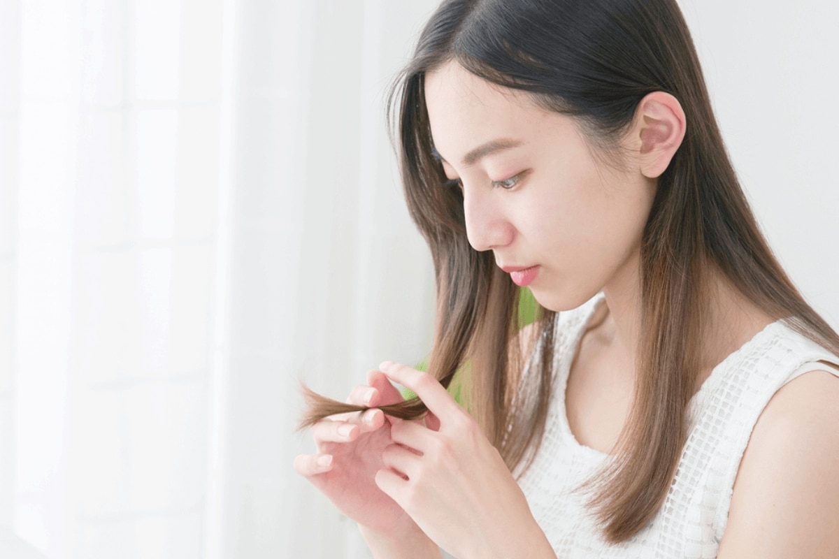 Cô gái cầm lọn tóc mỏng trên tay và quan sát