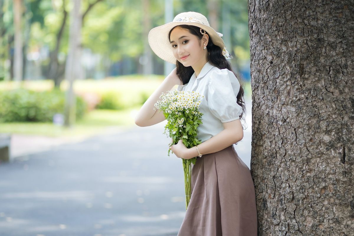 cô gái mặc chân váy màu nâu và áo sơ mi màu trắng phong cách Vintage aesthetic tay ôm bó hoa
