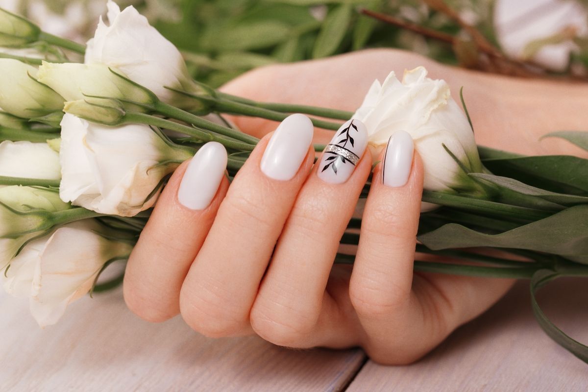 Móng tay giả đẹp màu trắng đang cầm hoa hồng trắng