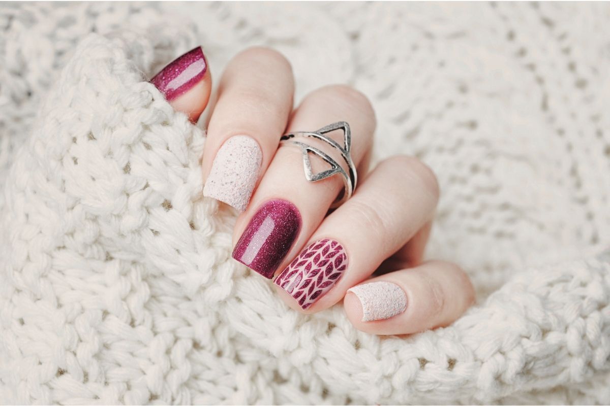 nail móng ngắn móng đỏ kim tuyến màu trắng ngón giữa đeo nhẫn trên nền vải len màu trắng