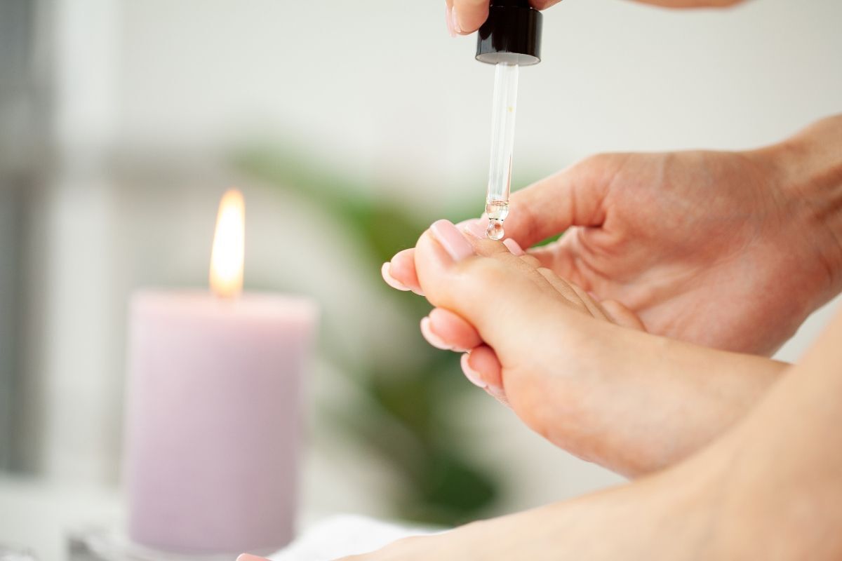 Nail chân đính đá sang trọng bàn chân đang được chăm sóc tinh dầu dưỡng từ ống nhỏ giọt