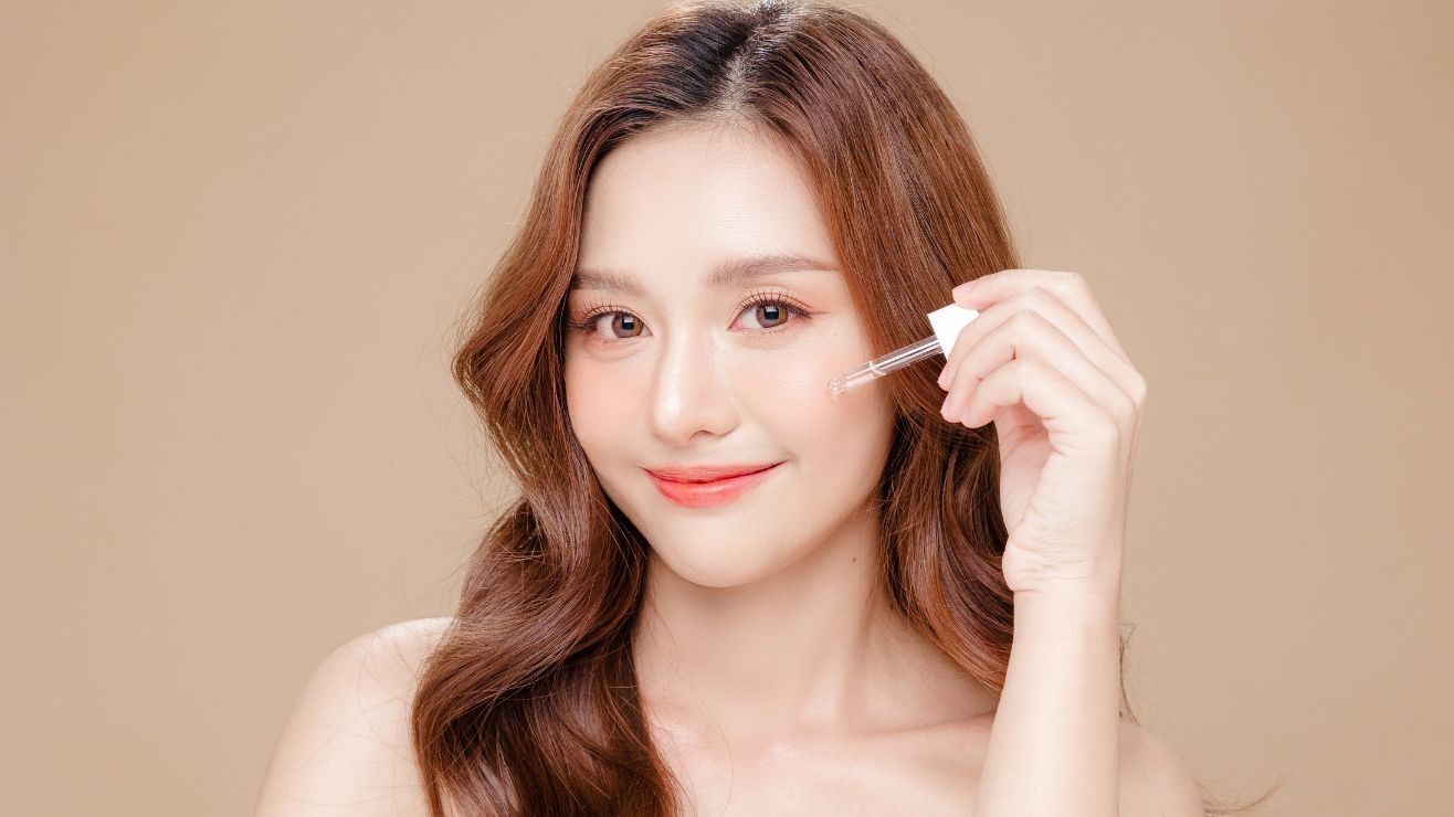 Cô gái cầm ống nhỏ tinh chất treatment thoa lên da 