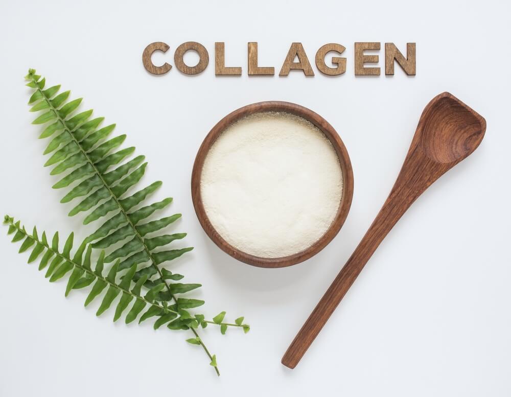 cách sử dụng collagen chữ collagen bằng gỗ nằm ở trên chén collagen và muỗng gỗ cùng hai nhánh lá