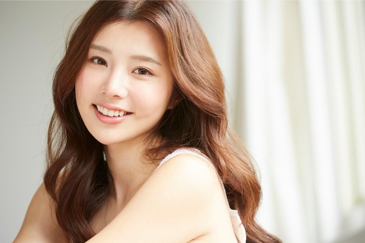 Cô gái tóc xoăn sóng nước đang nghiêng đầu mỉm cười