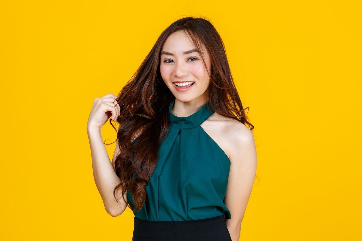 Tóc xoăn hàn quốc góc nghiêng cô gái mặc áo yếm màu xanh cổ vịt phía sau là phông nền vàng